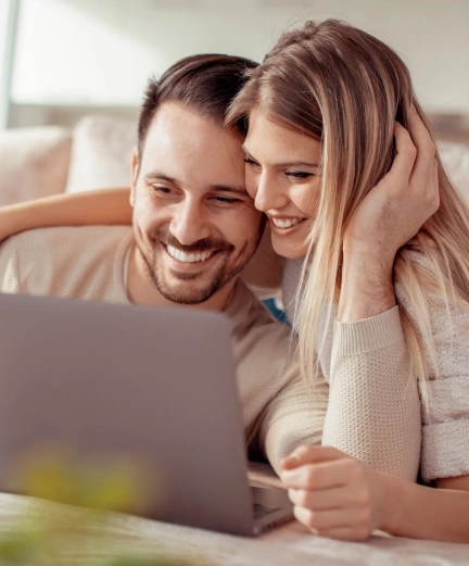 casal sorrindo olhando para notebook 